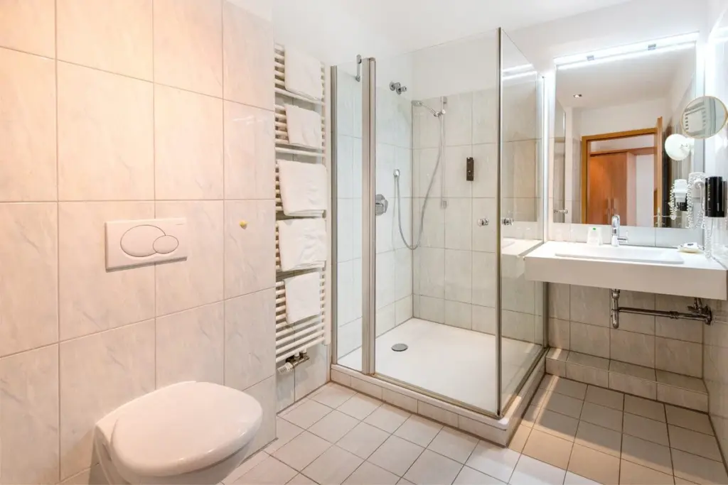 Modernes Badezimmer mit weißen Fliesen, hellen Armaturen und zeitgenössischem Comfort-Design.