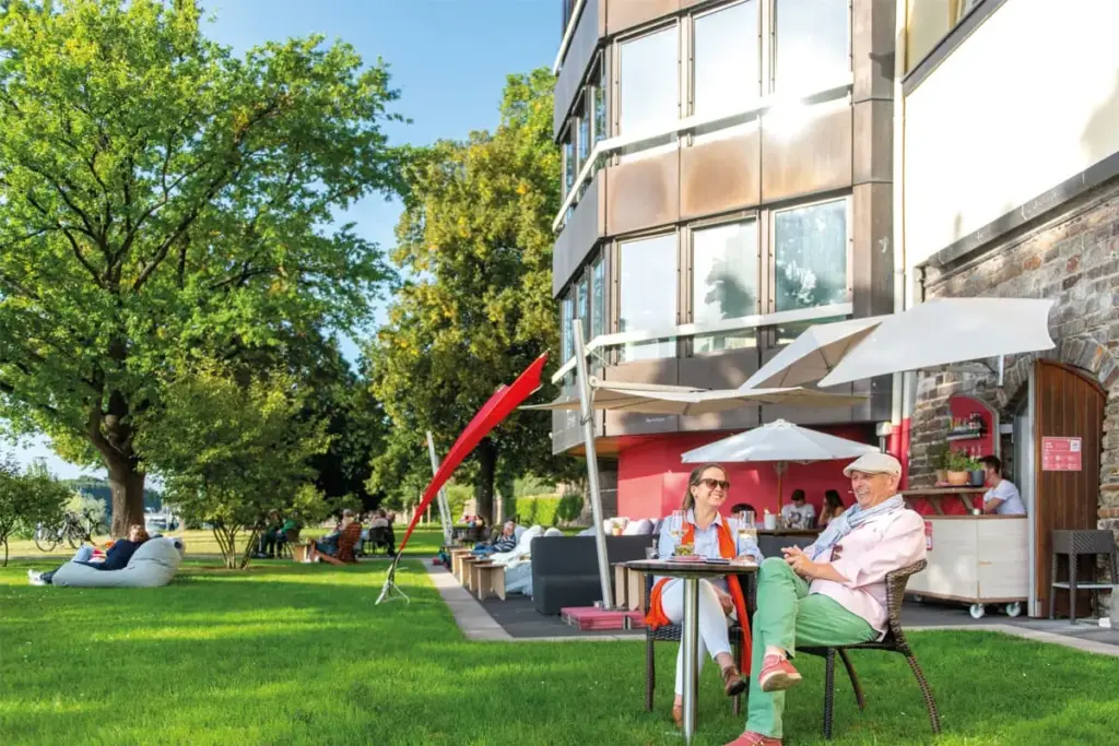 Moderne Lounge oder Bar mit grüner Akzentwand, rotem Sofa und zeitgenössischem Design am Rheinufer.