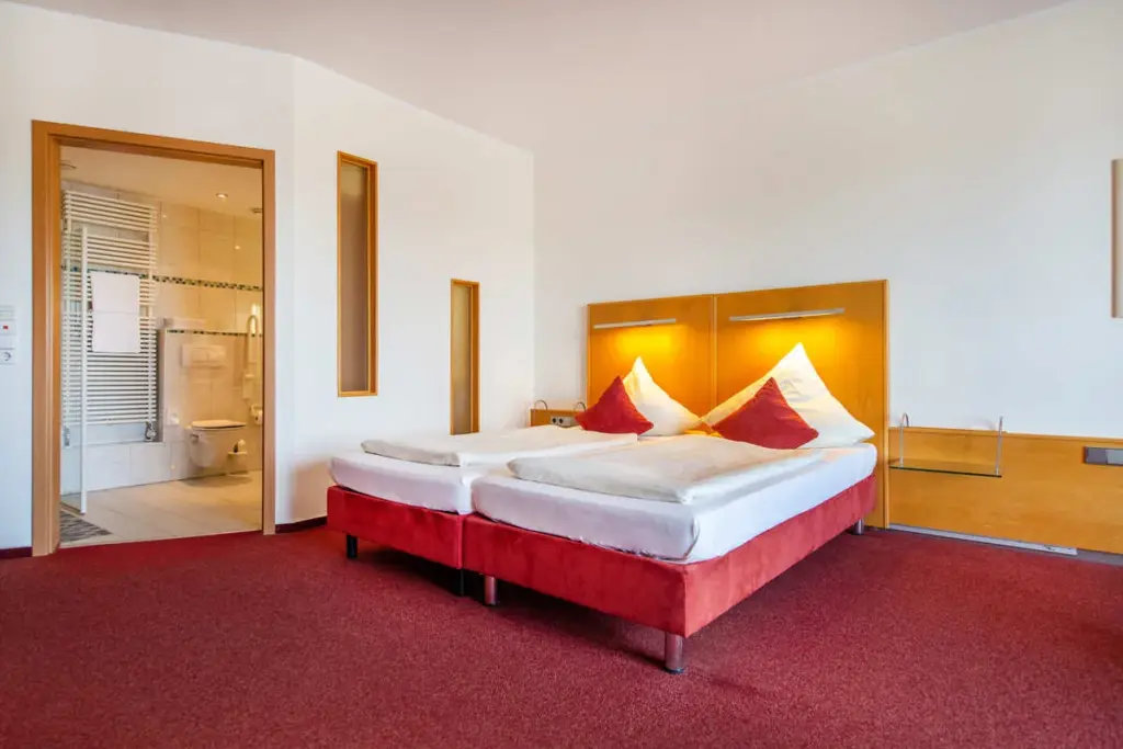 Gemütliches Hotelzimmer mit warmem Licht, Holzelementen und komfortabler Bettausstattung mit goldenen Farbtönen.